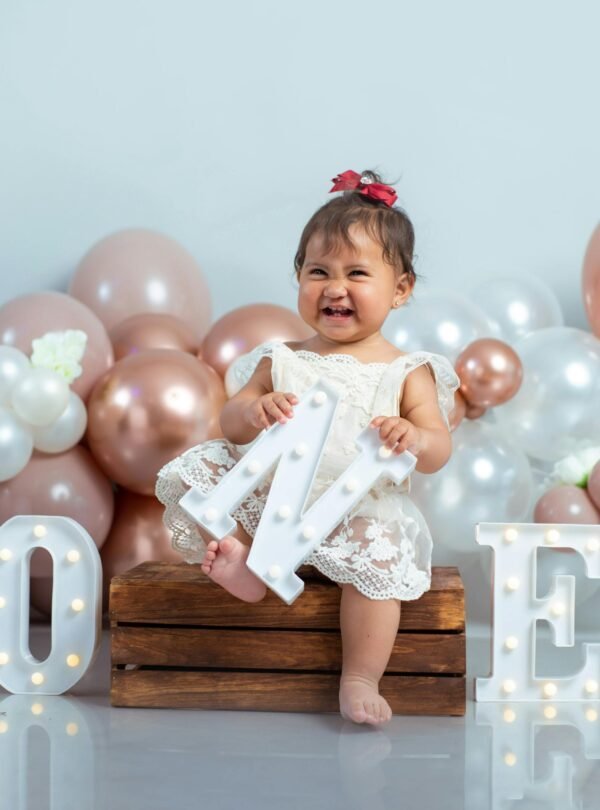 Cute baby girl celebrating her first birthday with balloons and decorations.