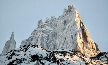 Stunning view of a snow-covered mountain peak illuminated by sunlight, highlighting its rugged beauty.