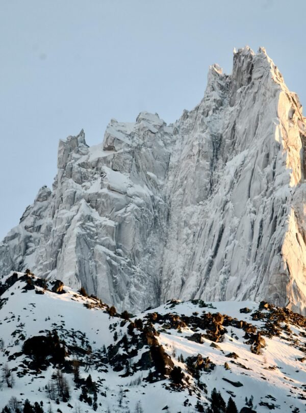 Stunning view of a snow-covered mountain peak illuminated by sunlight, highlighting its rugged beauty.